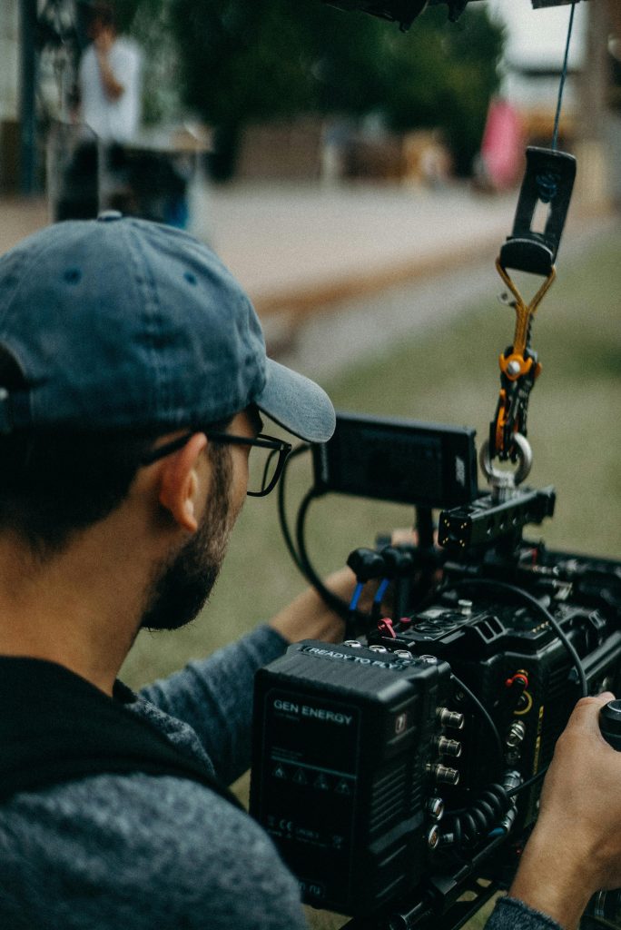 pexels photo 2773498 2773498 A focused filmmaker operating a cinema camera outdoors during daylight, capturing a creative video shoot.